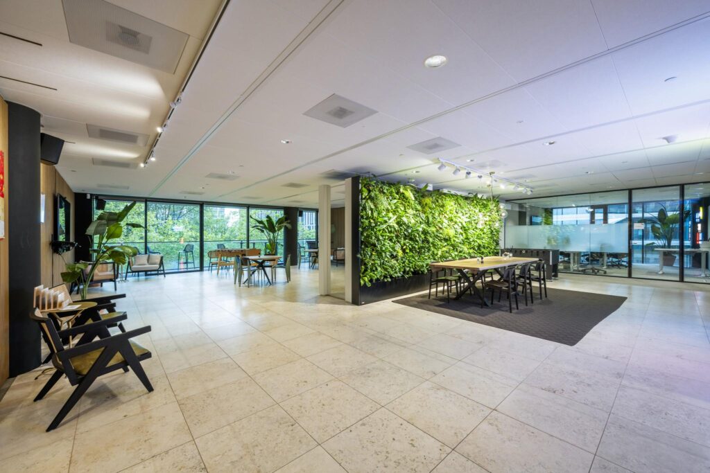 Modern office space on Gustav Mahlerlaan with a green plant wall, large windows, and seating areas.